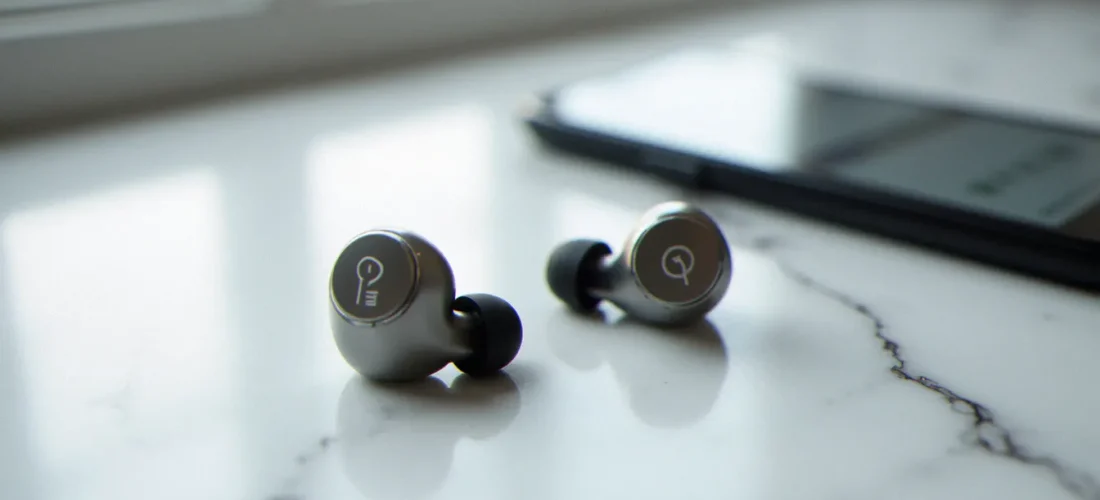 Bouchons d'oreilles Loop Experience Pro posés sur marbre blanc avec smartphone affichant un champ code promo Loop Earplug